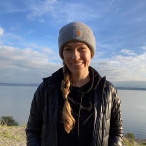 Lorraine standing in front of a lake in winter clothing, smiling at the camera.